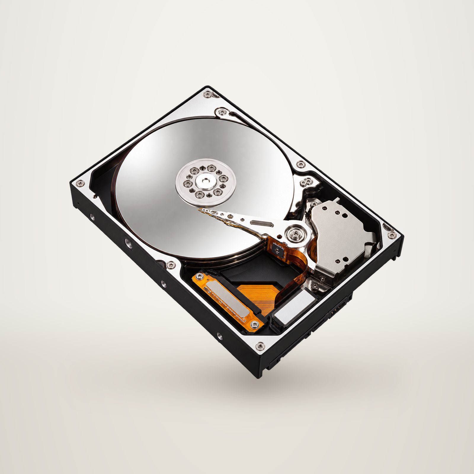 Un disque dur interne ouvert laisse voir son plateau métallique brillant et le bras de lecture, sur fond noir uni.