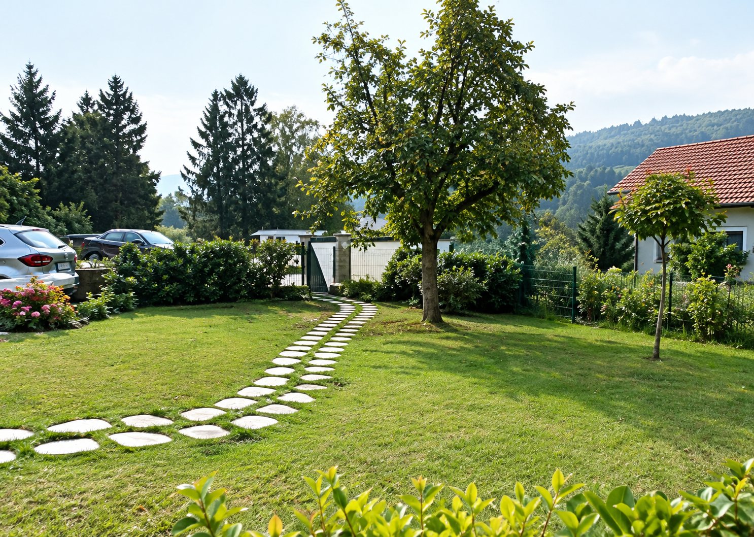 Un jardin verdoyant avec une pelouse tondue traversée par un chemin de dalles rondes, entouré d'arbres et de maisons.