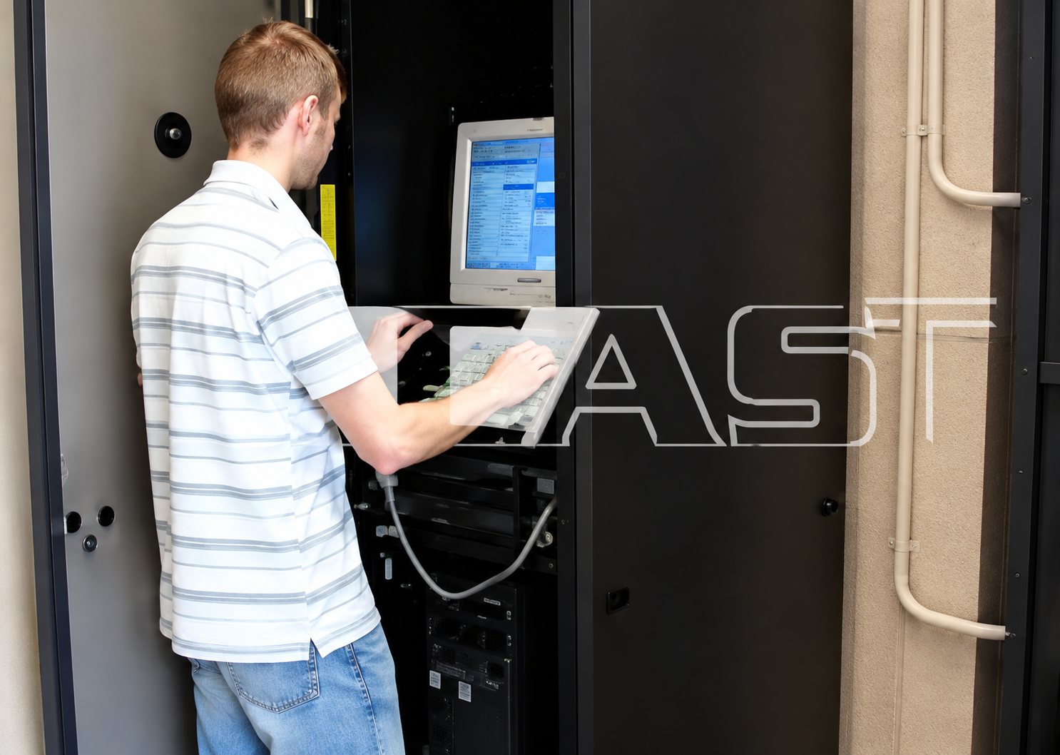 Technicien utilisant un terminal devant une armoire informatique.
